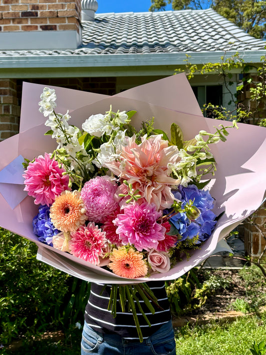 Bouquet of colorful flowers held by a person outdoors 