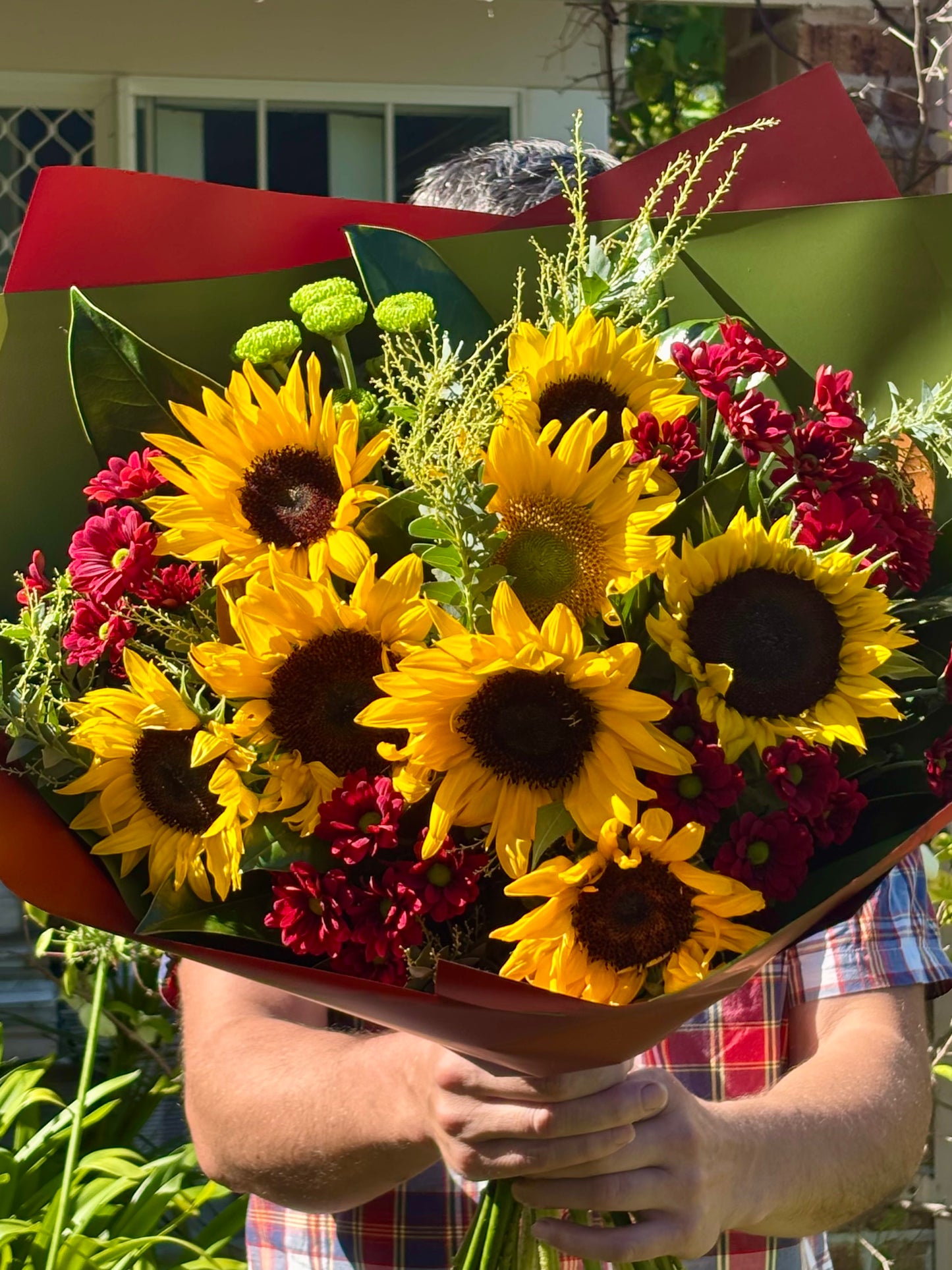 Large sunflower bouquet with crimson chrysanthemums, lime green button flowers and golden filler, wrapped in olive green and red paper”